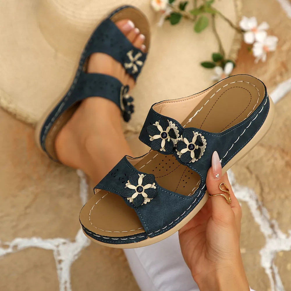 Navy blue sandals with floral appliqué and cut-out details.