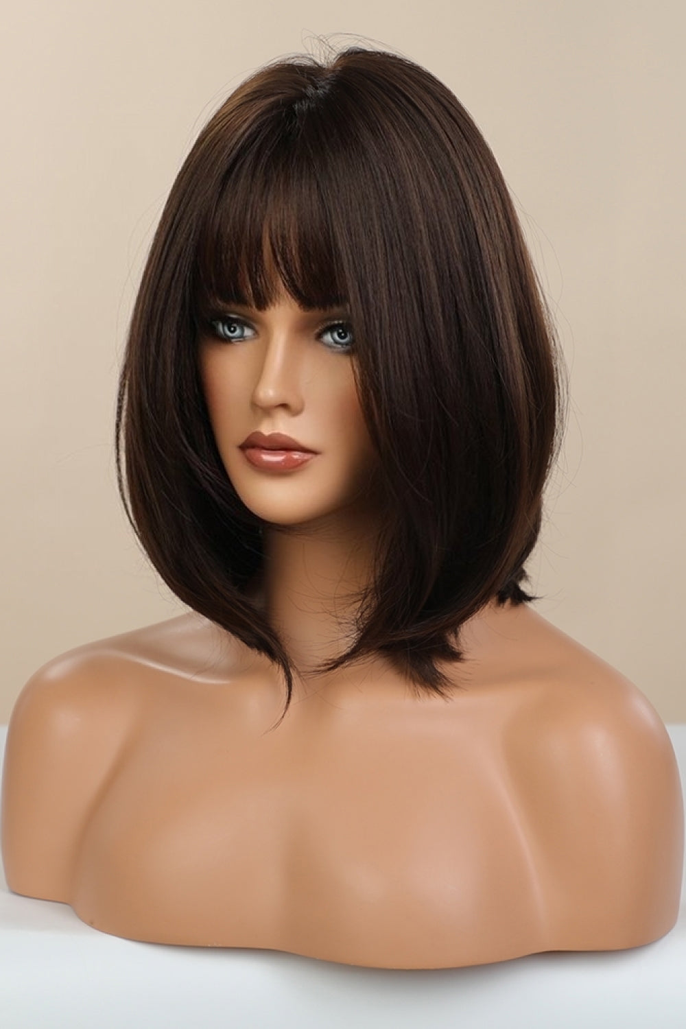 Brown bob wig with wispy bangs on a mannequin bust.