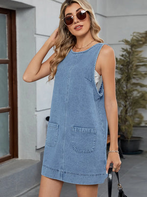Sleeveless light blue denim pinafore dress with front pockets and a rounded neckline.