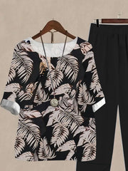 Floral print half sleeve top and black pants set with white cuffs and neckline.