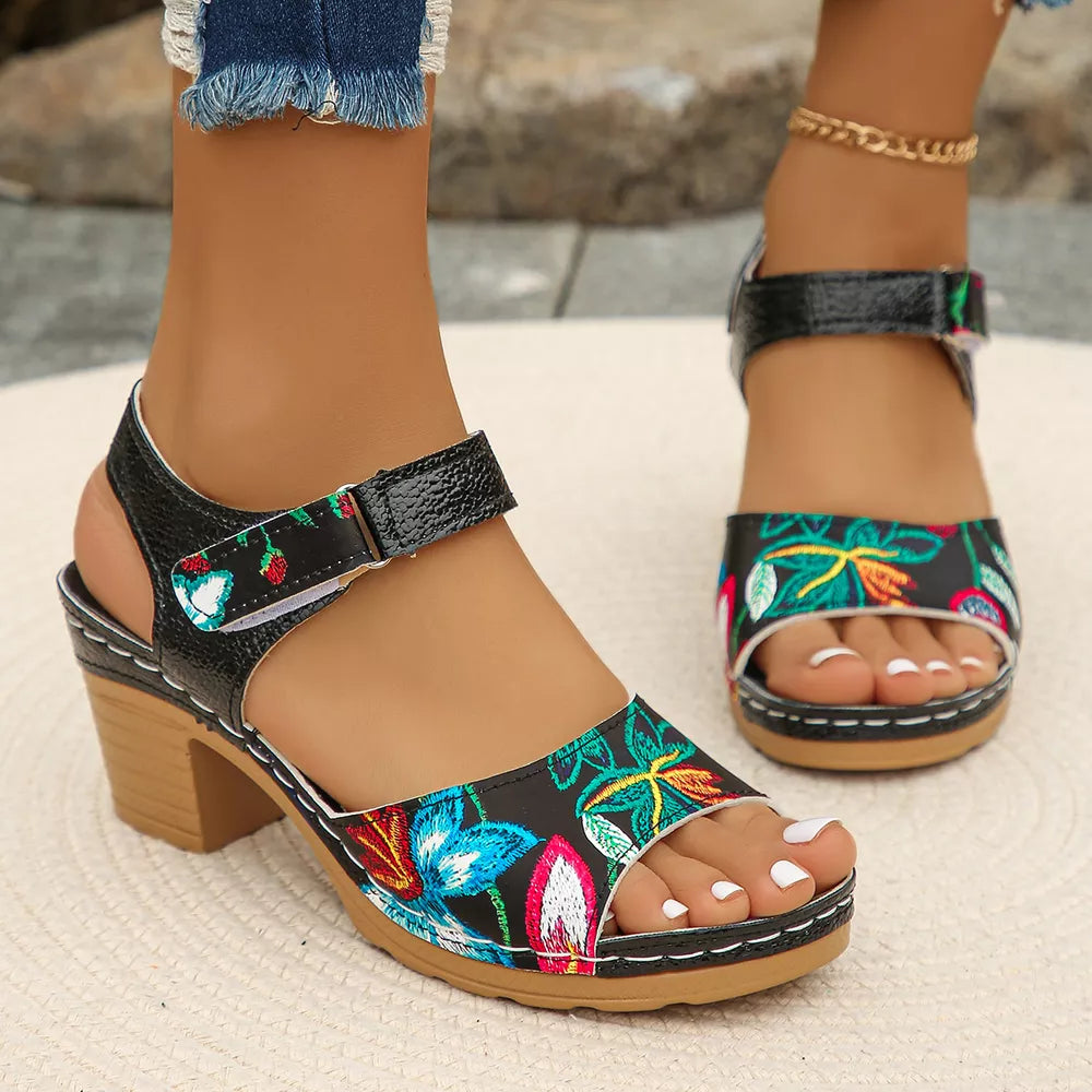 Black floral open-toe sandals with adjustable strap and block heel.