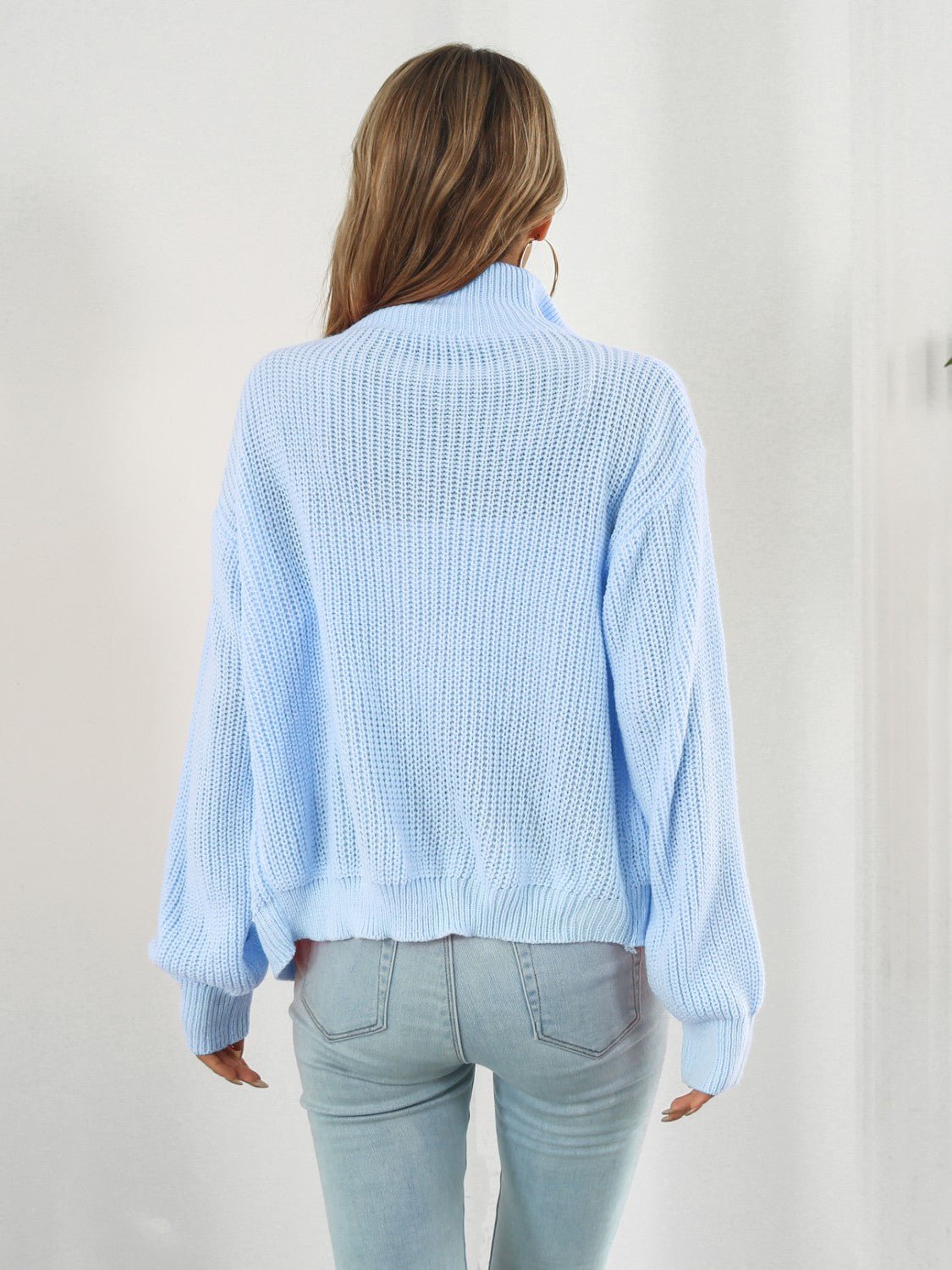 Pastel blue ribbed knit zip-up sweater with a mock neck and long sleeves.
