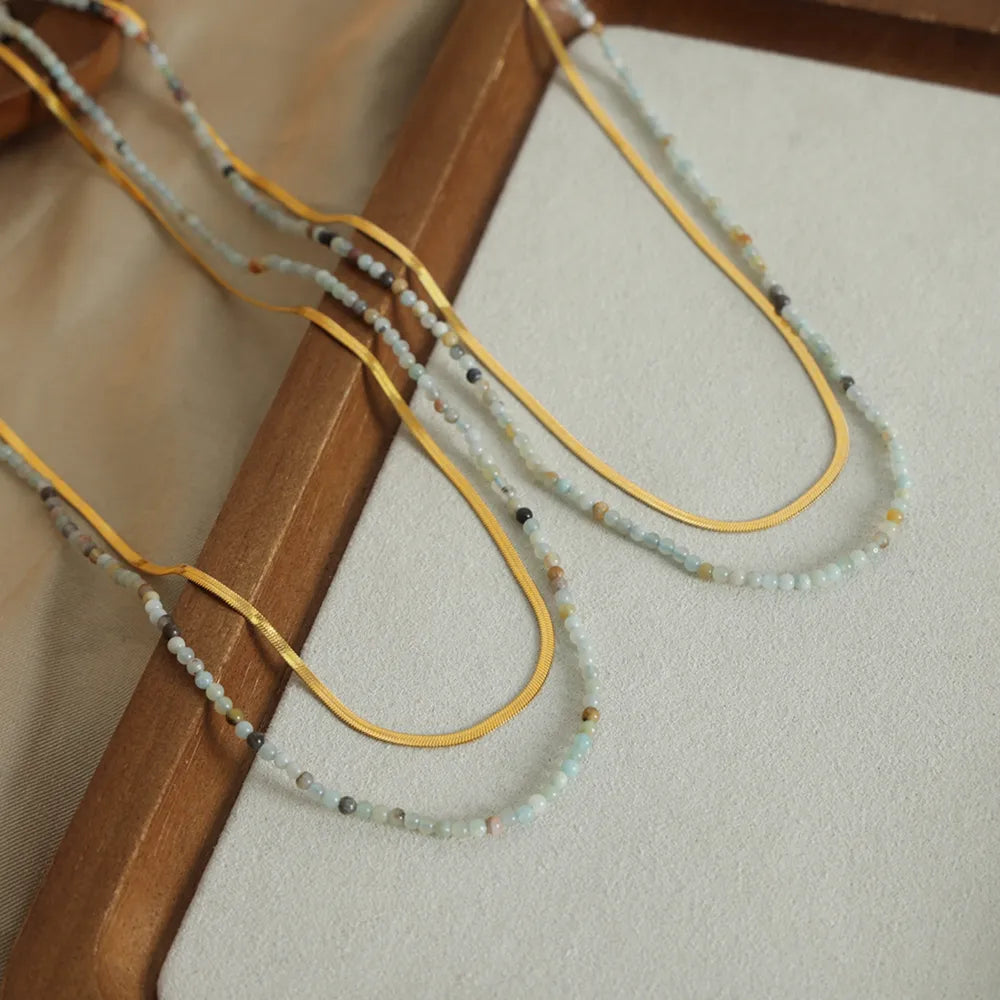 Gold layered necklaces with small beaded strands and flat snake chains