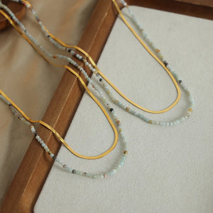 Gold layered necklaces with small beaded strands and flat snake chains