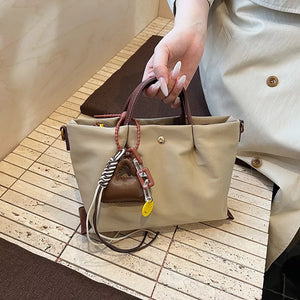 Compact nylon handbag in Khaki with brown handles and playful charms.