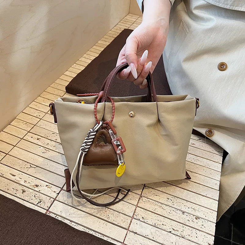 Compact nylon handbag in Khaki with brown handles and playful charms.