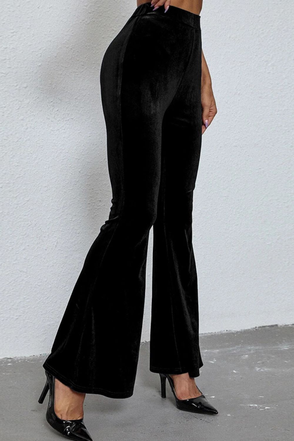 Black velvet hourglass flare trousers with a high waist, styled with black heels.