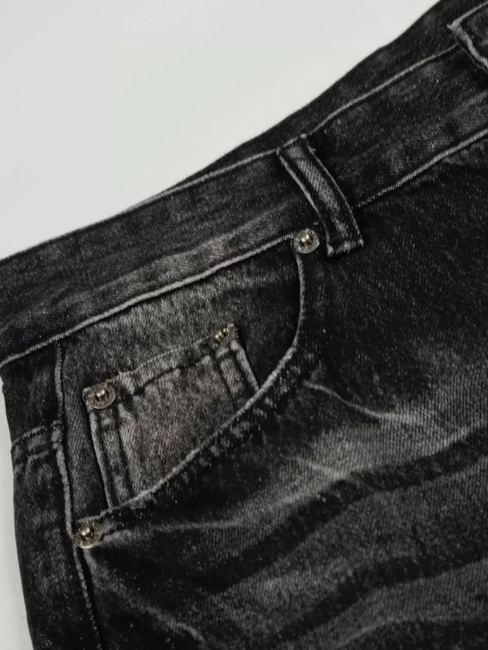 Men's black vintage wash wide leg jeans with distressed details.