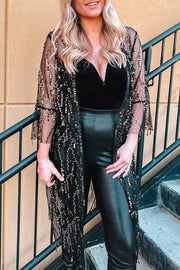 Black sequin duster with flared sleeves and fringe detail over a black velvet bodysuit.