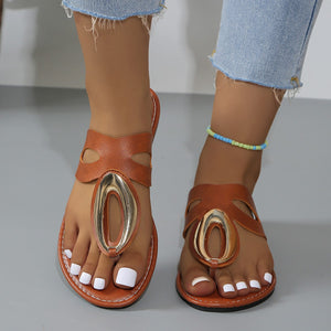 Brown open-toe sandals with golden oval accent and cut-out details.