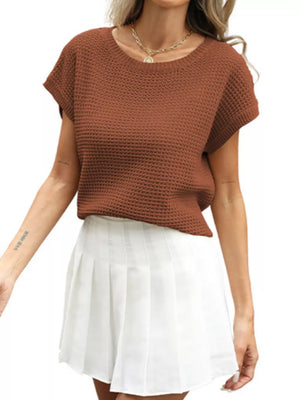 Apricot openwork knit short sleeve top with crew neck, styled with a white pleated skirt.