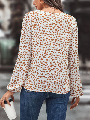 White blouse with brown animal print, long sleeves, and tie neck.
