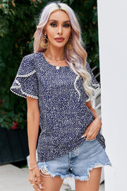 Dark blue dotted polyester blouse with flutter sleeves and pom-pom trim.
