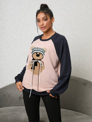 Blush pink raglan sweatshirt with a sequined teddy bear appliqué and drawstring details.