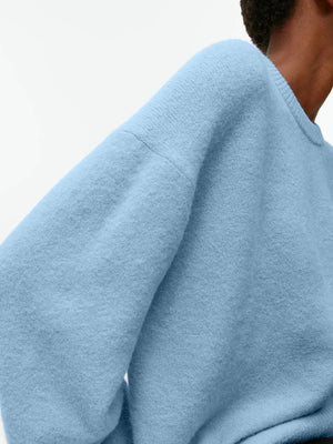 Light blue oversized brushed knit crewneck sweater with a soft texture.