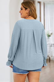 Light blue textured blouse with shirred cuffs and a slit neckline.