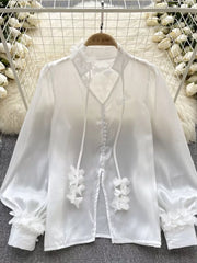 White sheer button-down shirt with delicate floral appliqué and bow details.