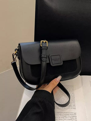 Chic two-tone crossbody bag in black with buckle detail and adjustable strap.
