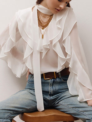 White chiffon blouse with V-neck, ruffle trim, and tie detail.