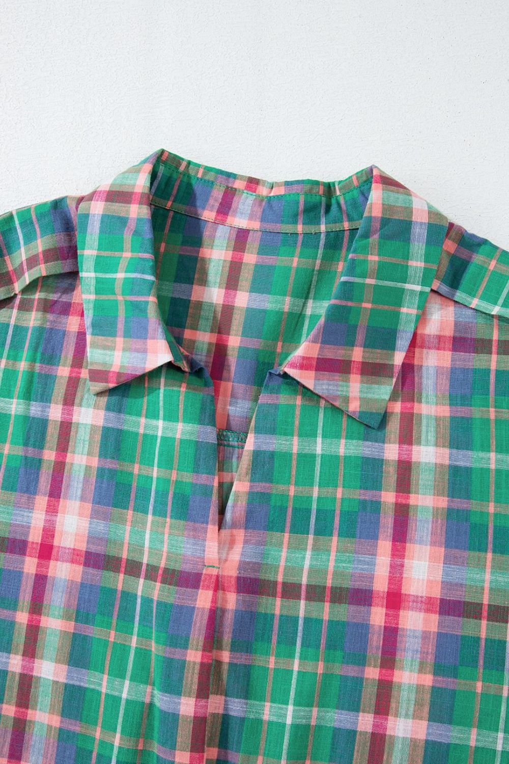Voluminous plaid blouse with a V-neck and spread collar in green, pink, and blue plaid.