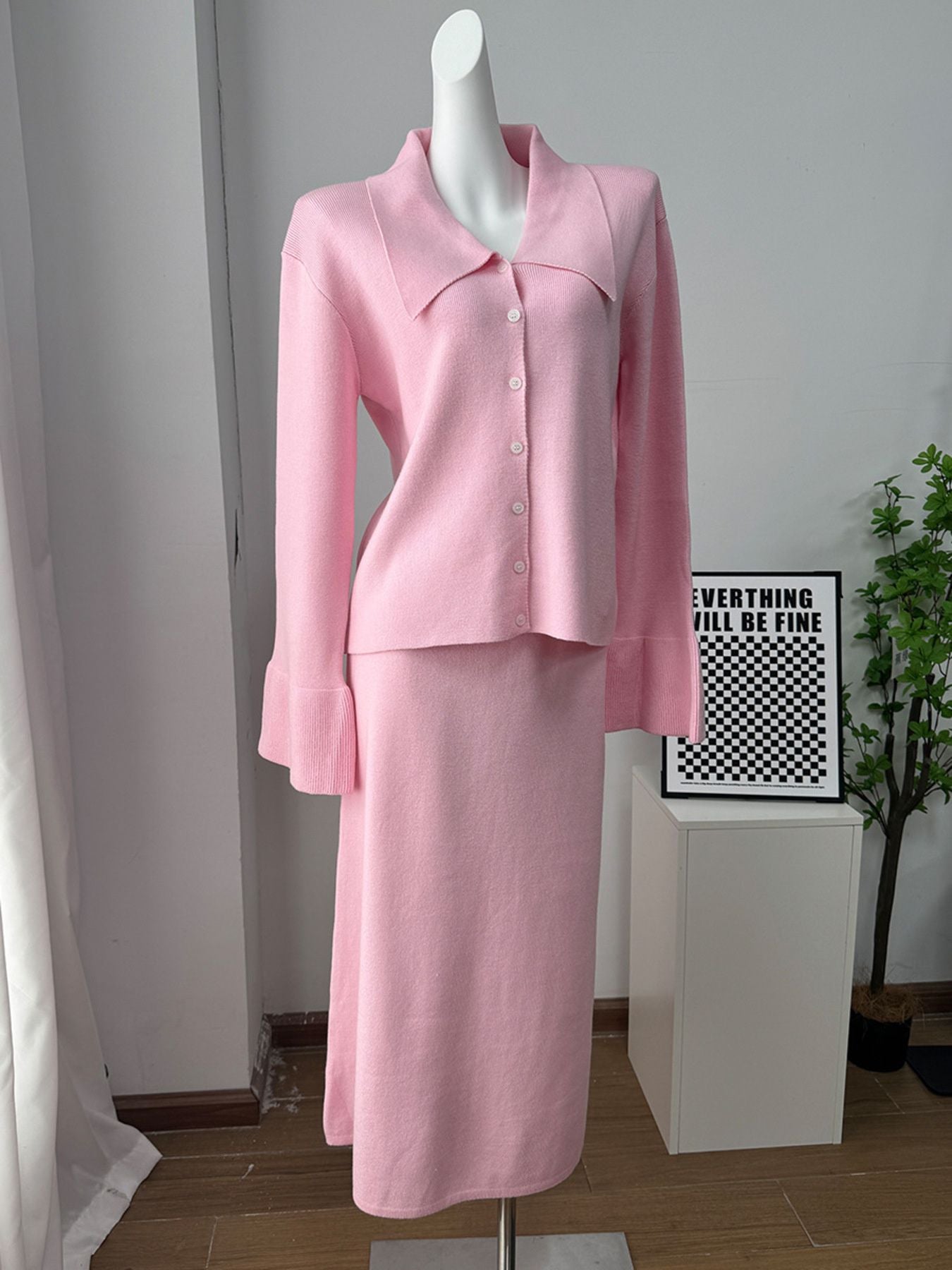 Pink ribbed knit cardigan with collar and button-down front, paired with a matching midi skirt.