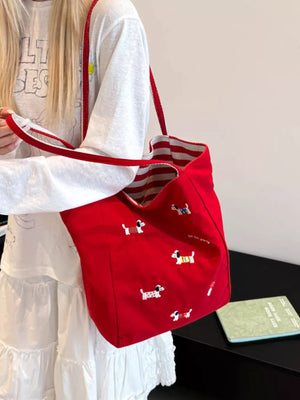 Red shoulder bag with embroidered dachshunds and striped lining.