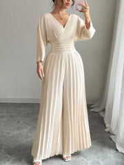 Elegant beige pleated wide-leg jumpsuit with cinched waist and V-neck.