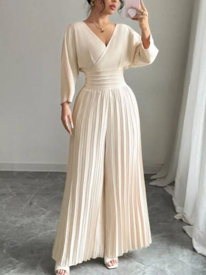 Elegant beige pleated wide-leg jumpsuit with cinched waist and V-neck.
