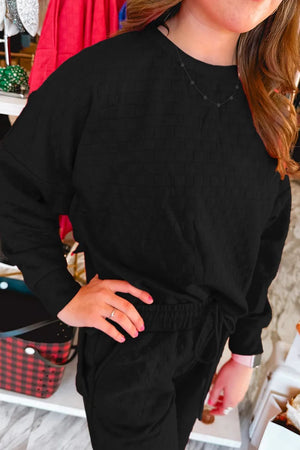 Black textured weave loungewear set with crew neck sweatshirt and drawstring pants.