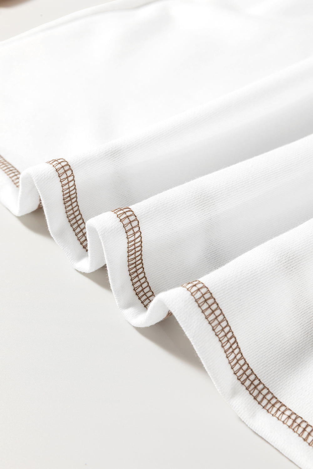 Textured raglan sleeve tee in white with brown contrast stitching detail.