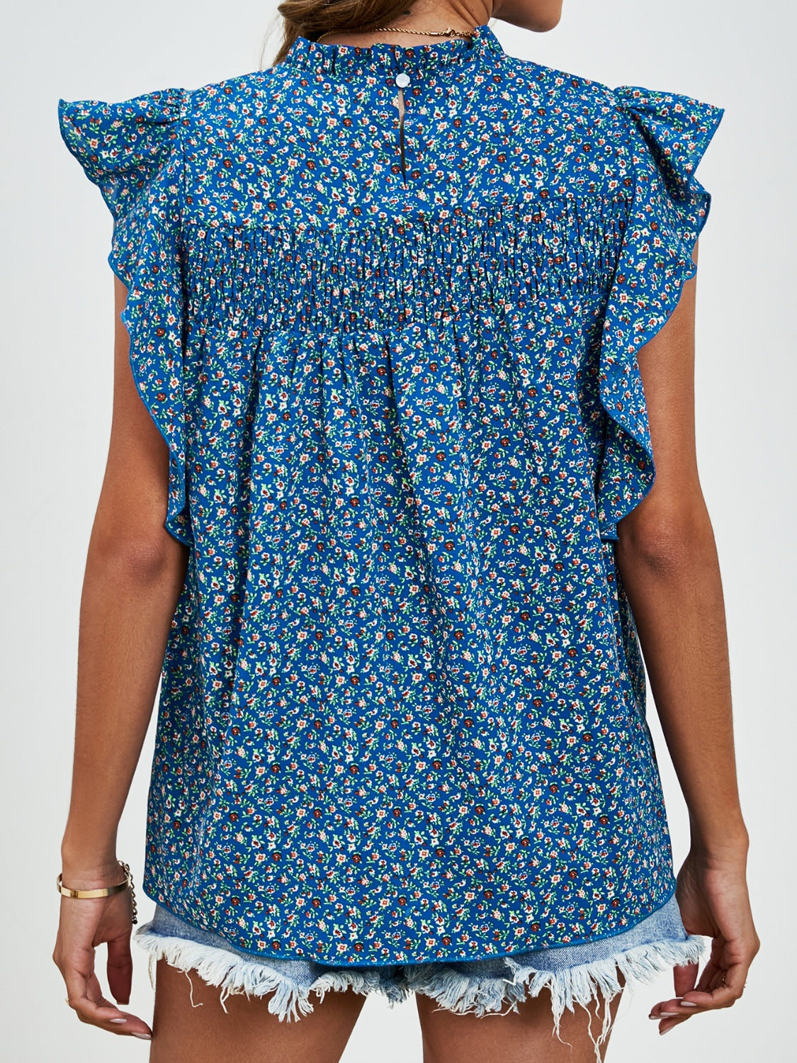 Smocked yoke ruffle sleeve floral blouse in dark blue with mock neck and button back.