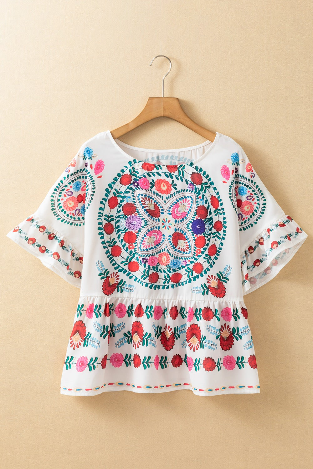 White peplum blouse with embroidered medallion and floral print, ruffle sleeves.