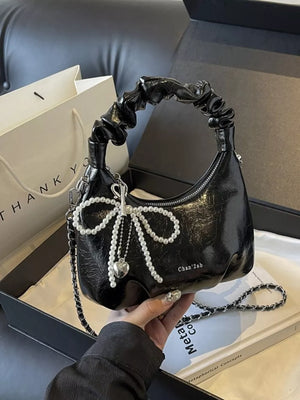 Black ruched mini crossbody bag with pearl bow detail and heart charm.