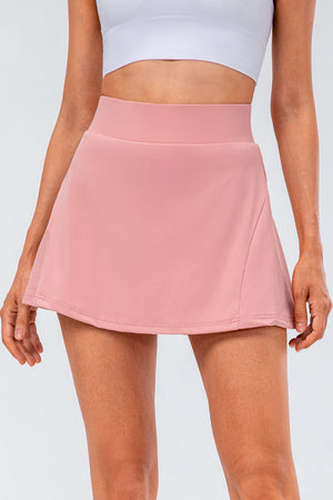 Blush pink performance skort with a wide waistband and subtle pocket detail.