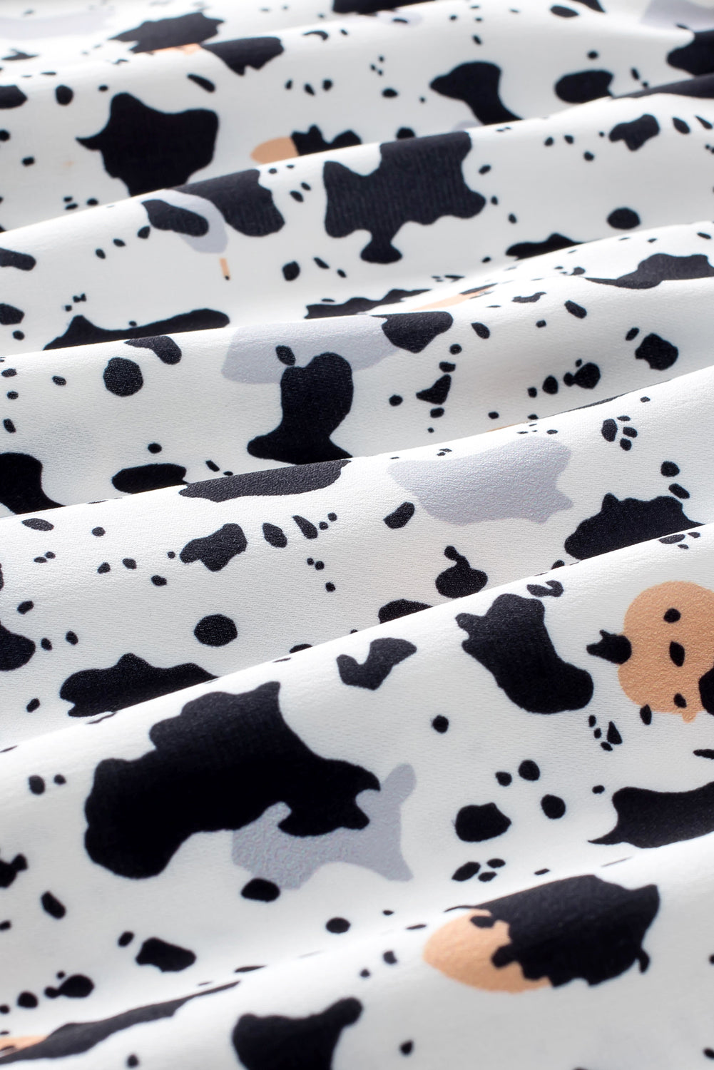 White blouse with black and tan abstract print and ruffle detail.