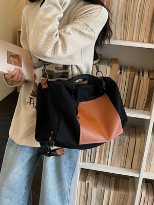 Black nylon crossbody bag with a brown contrast pocket and leather trim.