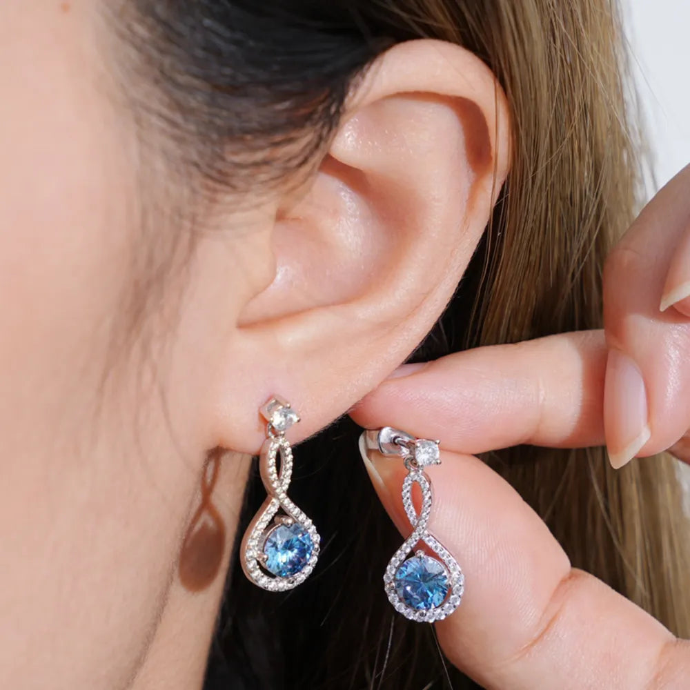 Infinity drop aquamarine earrings with white gold setting and diamond accents.