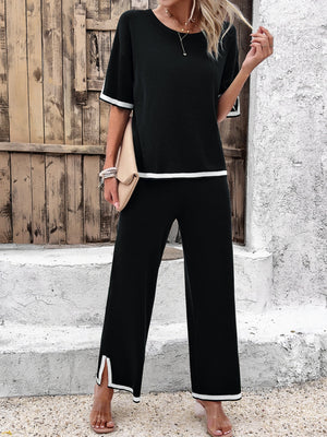 Black knit co-ord set with white contrast trim on crewneck top and wide-leg pants with side slits.