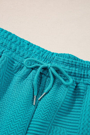 Turquoise textured co-ord shorts with drawstring waist and chevron pattern detail.