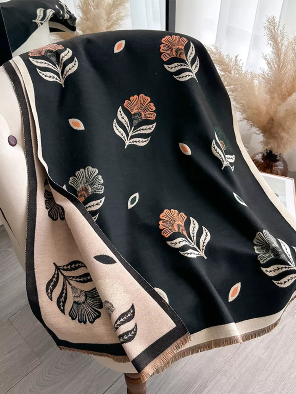 Black floral print fringed shawl with beige border and fringe detail.