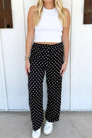 Chic polka dot wide-leg maternity trousers in black with white dots, featuring a comfortable elastic waist.
