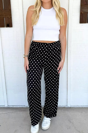 Chic polka dot wide-leg maternity trousers in black with white dots, featuring a comfortable elastic waist.