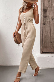 Beige pleated jumpsuit with V-neck, button front, tie waist, and wide legs.