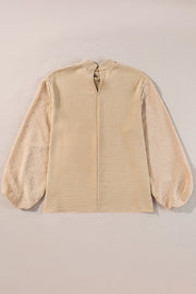 Tan textured blouson top with Swiss dot sheer balloon sleeves and mock neck.