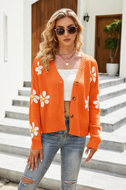 Orange acrylic knit cardigan with white daisy print, V-neck, button front, and long sleeves.
