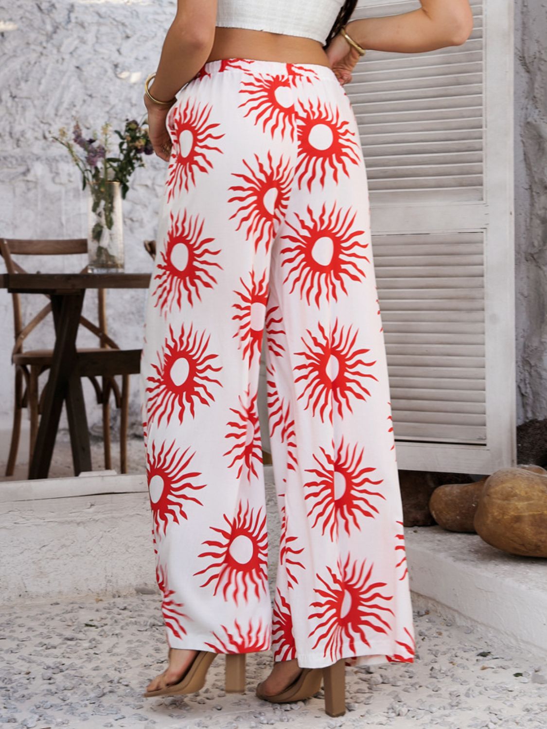 Geometric print wide-leg trousers in white with red sun pattern and drawstring waist.