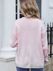 Blush pink acrylic intarsia knit cardigan with a floral pattern detail on the sleeve.