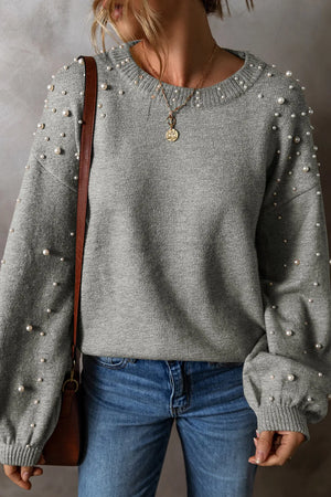 Gray pearl-embellished long sleeve sweater with crew neck, styled with jeans.