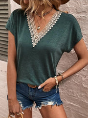 Dark green dolman sleeve top with lace trim V-neck, styled with denim shorts.