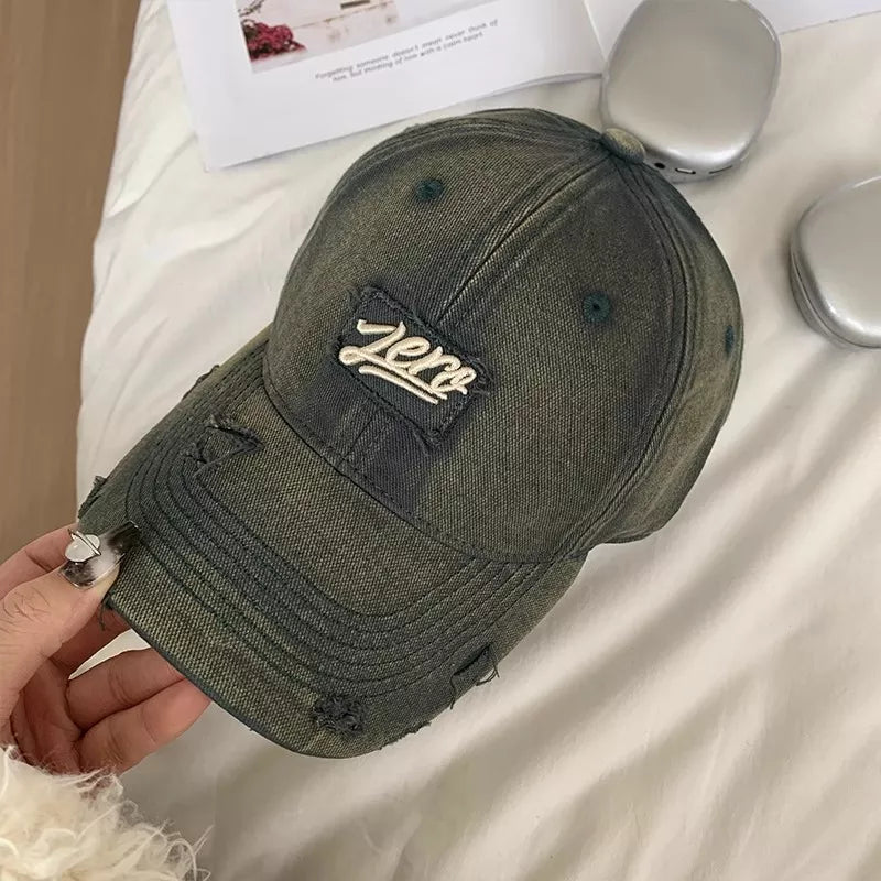 Distressed cotton baseball cap in dark gray with a "zero" patch and frayed details.